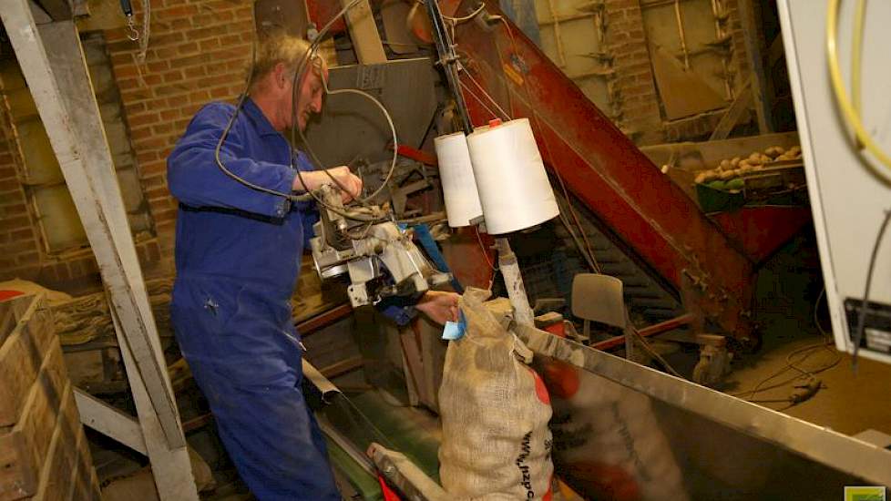 Broer Wiert Paul Berghuis staat bij het opzakken. Hij naait de zakken dicht en via een transportbandje gaan de zakken naar de palletiseermachine.