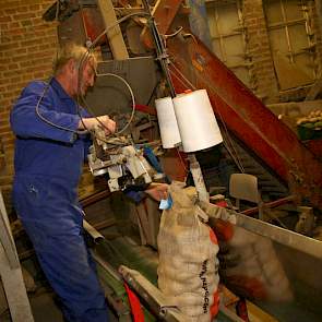 Broer Wiert Paul Berghuis staat bij het opzakken. Hij naait de zakken dicht en via een transportbandje gaan de zakken naar de palletiseermachine.