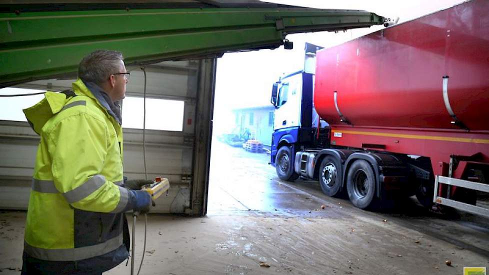 Chauffeur Nico Bijland bestuurt via een afstand bediening de boxenvuller, zodat hij de vrachtwagen op de juiste manier vol laadt.