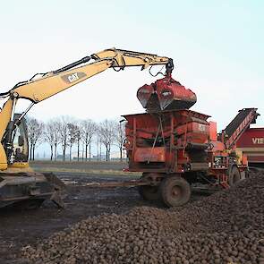 De kraan stort de aardappelen in de schoner, die ze vervolgens in de vrachtwagen stort.